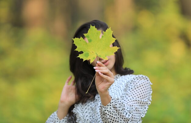 autumn portrait of a beautiful young woman hiding in the foliage