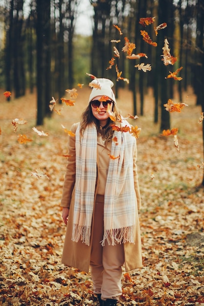 写真 落ち葉を持つ若い女性の秋の肖像画 秋の公園を歩く