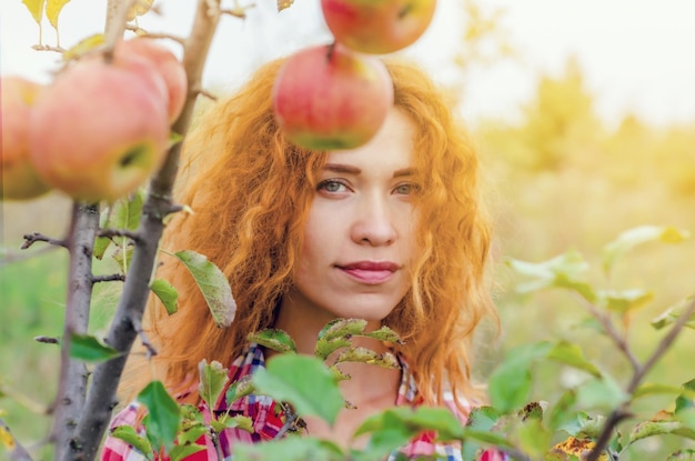 放棄された生い茂ったリンゴ園の若い女性の秋の肖像画