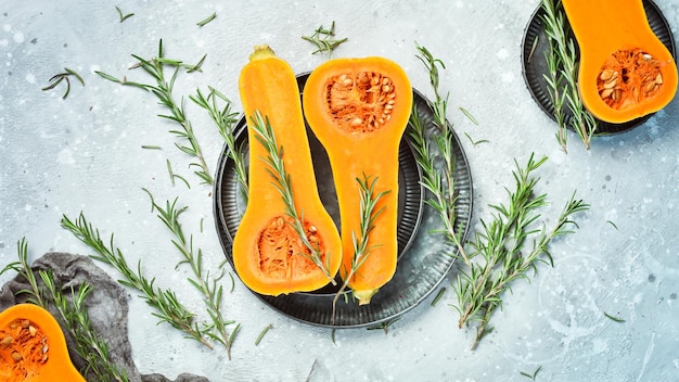 Autumn pumpkin banner fresh sliced pumpkin with rosemary and spices on a stone background top view