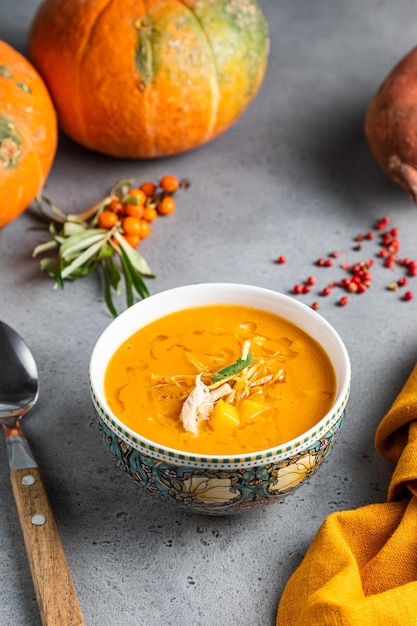 Autumn pumpkin cream soup with rosemary and paprika in dark wooden background