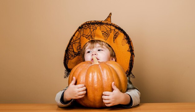 Foto ricette d'autunno bambino carino in cappello di strega con grande zucca per il giorno del ringraziamento cucinare o halloween