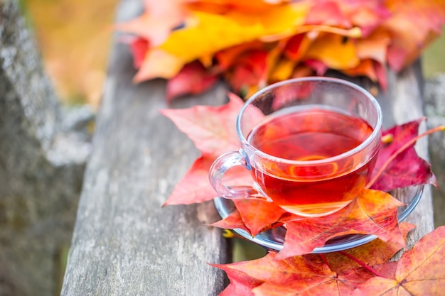 秋の赤茶。木の板に紅葉とお茶のカップ。