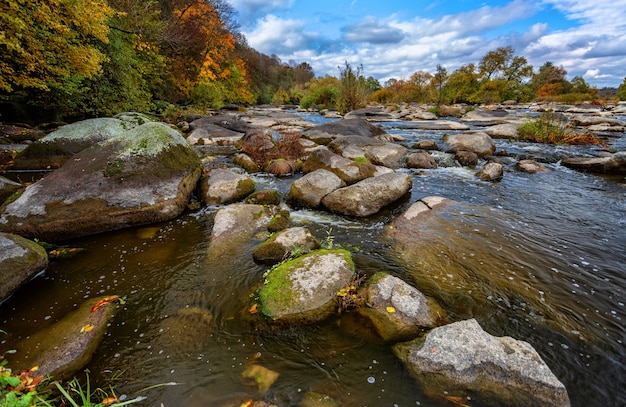 Autumn river with beautiful large stones blue sky and trees