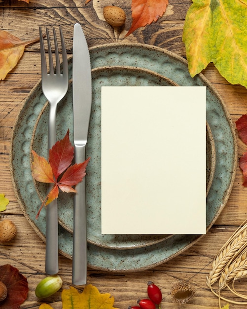 Autumn rustic table setting with blank card between leaves and berries top view mockup