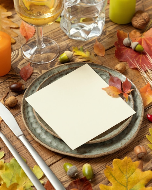 Autumn rustic table setting with red yellow and orange leaves berries and blank card close up mockup