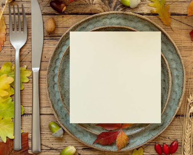 Autumn rustic table setting with red yellow and orange leaves berries and blank card top view mockup