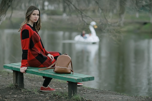 autumn sad girl outdoor / autumn weather, portrait of a young adult girl in a coat in a cage, Scottish style