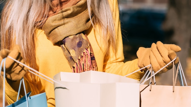 Photo autumn sale cropped shot of lady looking into shopping bags, checking bought items