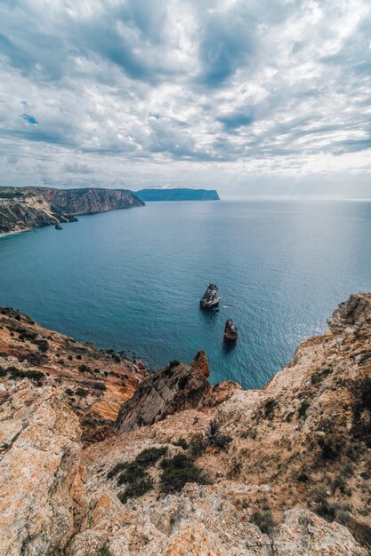 Осенний морской пейзаж с пасмурным небом и вулканическим скалистым побережьем спокойное море на фоне