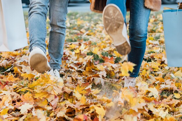 Autumn season leisure Cropped shot of couple walking in park after shopping having fun playing with yellow maple leaves