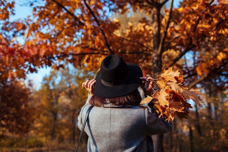 Photo autumn season. young woman walking in fall park admiring nature and holding bouquet of leaves