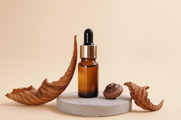 Autumn showcase made of natural stone autumn foliage glass brown bottle essential oil Podium presentation cosmetics is made of wood on beige background Minimalistic branding scene