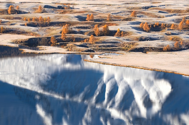 Foto paesaggio della montagna siberiana di autunno con i larici gialli e il lago alpino