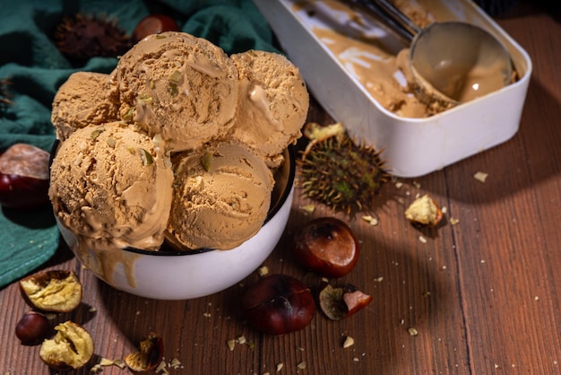 Autumn spicy ice cream with the roasted chestnut taste with spices on a wooden background with fresh and roasted chestnuts