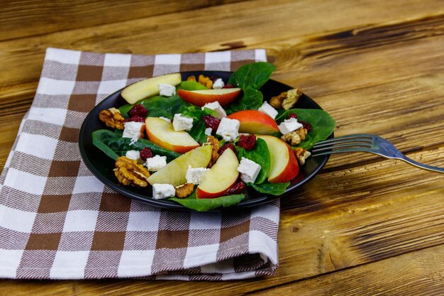 사과 페타 치즈 호두와 나무 테이블에 말린 크랜베리를 곁들인 가을 시금치 샐러드 건강한 채식 음식