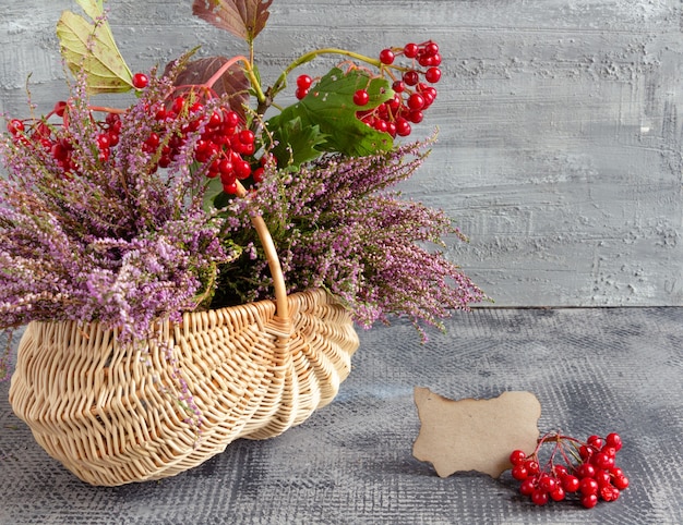 Autumn still life on concrete background basket with heather and viburnum and empty postcard thanksg...