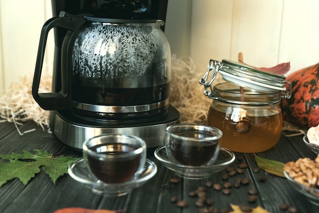 ナッツと豆とテーブルの上のコーヒーと蜂蜜の秋の静物カップ