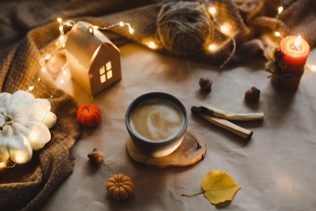 Autumn still life details in cozy home interior with a cup candles plaid hygge halloween and thanksg...