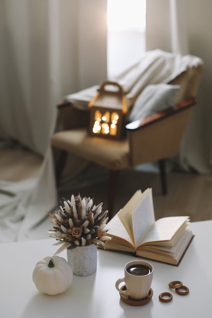 Autumn still life and home decor in rustic style with a pumpkin book cup and flowers