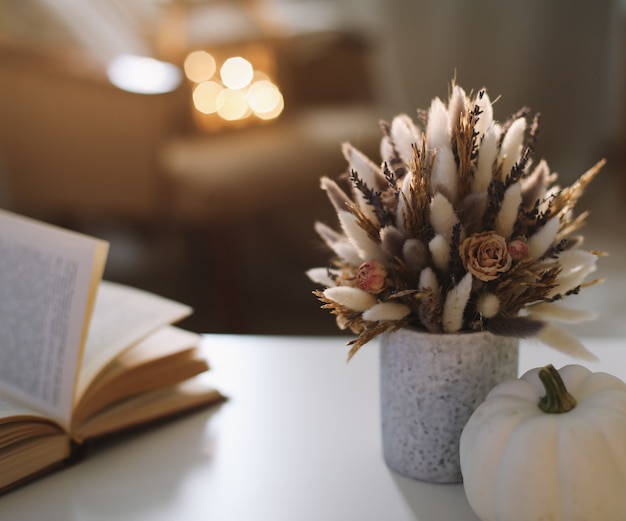 Autumn still life and home decor in rustic style with a pumpkin book cup and flowers