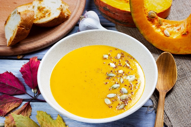 Autumn still life pumpkin cream soup with pumpkin seeds and pieces halloween theme