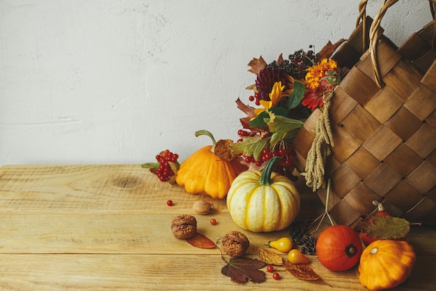 Autumn still life Stylish pumpkins autumn flowers in basket on rustic table Happy Thanksgiving