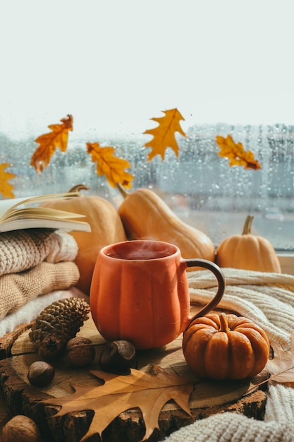 Autumn still life on the windowsill a cup of tea candles pumpkins leaves thanksgiving house interior