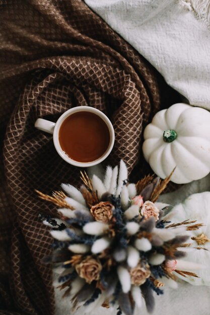 Natura morta autunnale con una tazza di caffè con fiori e zucche su un accogliente plaid a letto autunno elegante ...