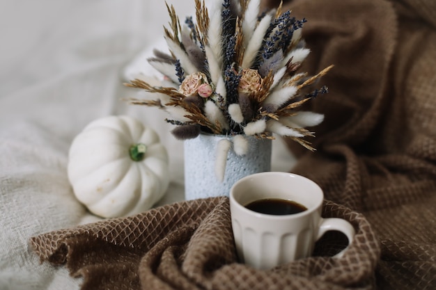 Photo autumn still life with a coffee cup with flowers and pumpkins on a cozy plaid