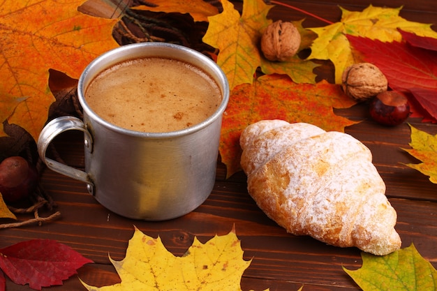 Autumn still life with cup of cappuccino and croissant