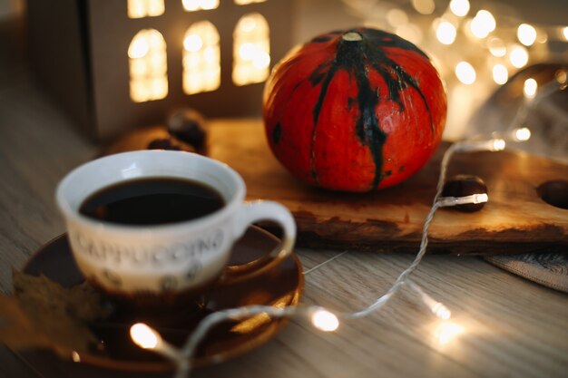 Autumn still life with a cup of coffee pumpkin and leaves on a cozy background