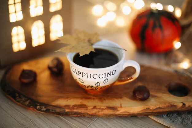 Autumn still life with a cup of coffee pumpkin and leaves on a cozy background