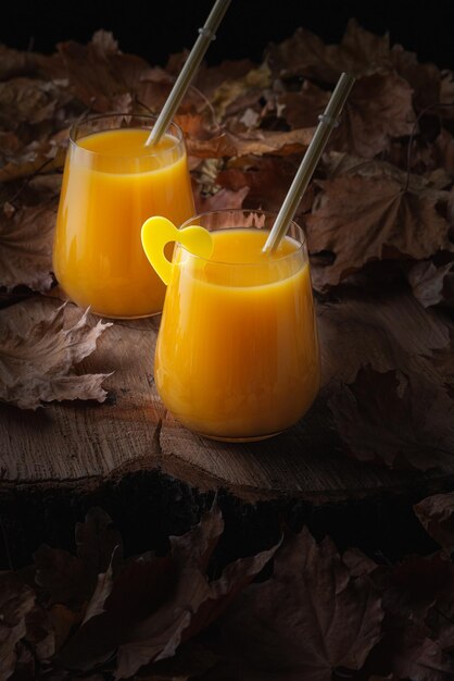 Autumn still life with orange juice and fallen leaves