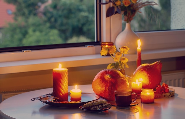 autumn still life with pumpkins burning candles and cup of tea