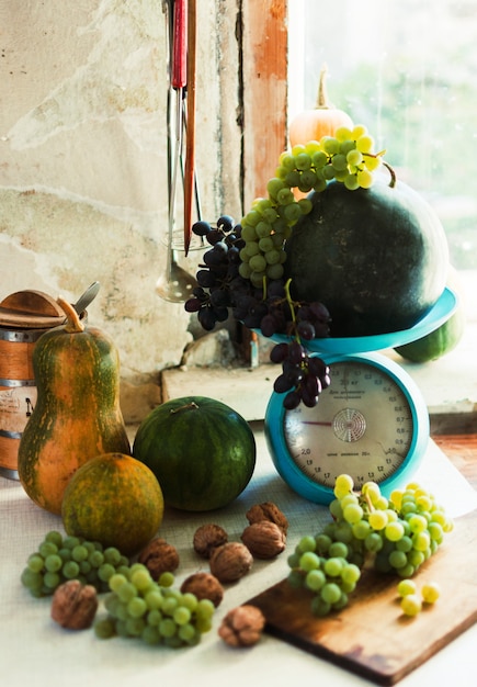 autumn still life with pumpkins,walnuts,melons, watermelon and grapes on  a wooden white table.