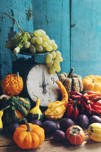 Autumn stilllife background with fresh organic fruits and vegetables Assortment of ripe plums grapes pumpkin persimmon and red peppers harvest or thanksgiving composition selective focus