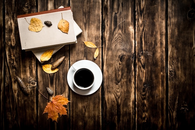 Caffè in stile autunnale con un vecchio libro su fondo in legno