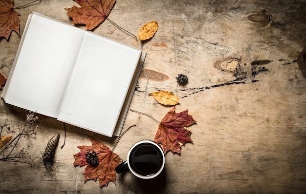 Autumn style. Open book with a hot Cup of coffee. On wooden background.