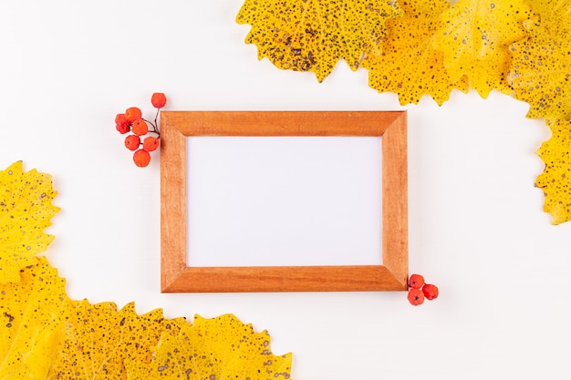 Autumn style photo frame with copyspace surrounded by dry yellow leaves