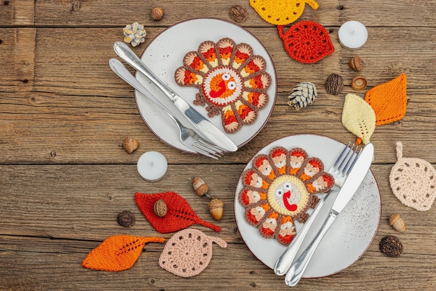秋のテーブルセット 感謝祭の食器 伝統的な秋の装飾 フラットレイ 祭りの快適な気分 手作り crocheted トルコと葉 木製の背景トップビュー