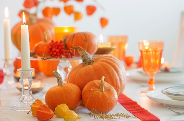 Autumn table setting with burning candles and pumpkins