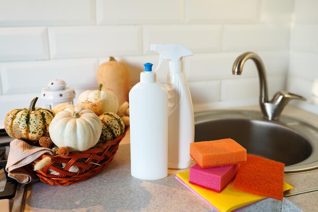 Autumn table with dish detergent dishwashing liquid with a sponge and pumpkins on kitchen near sink