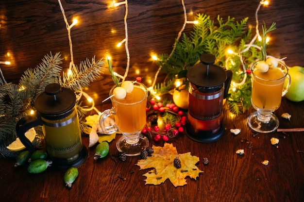 Autumn tea in french press and citrus tea in transparent mug with apple, feijoa and lychee on the table in restaurant