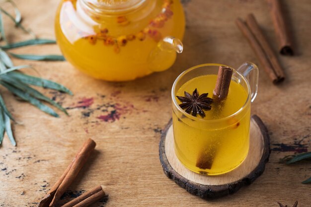 Autumn tea in a sea buckthorn mug with a cinnamon stick on a wooden background autumn mood