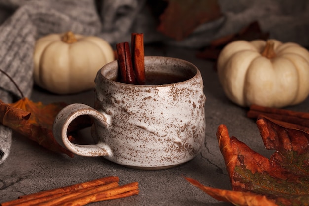 Foto tè autunnale con cannella. tè nella scena autunnale. foglie e zucche di autunno