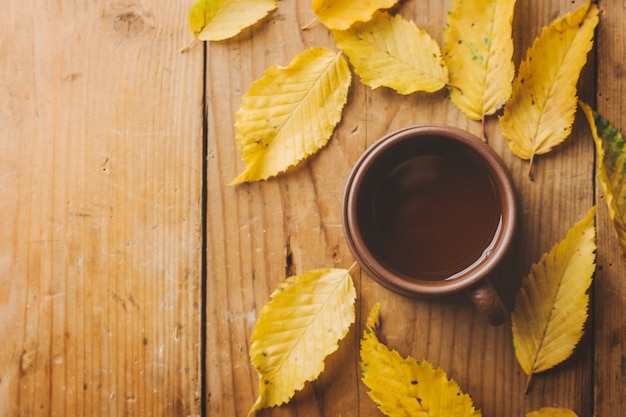 Autumn tea on wooden table with leaves