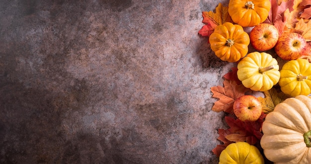 Autumn and thanksgiving decoration background concept with fall leaves pumpkin and seasonal autumnal decor on stone background top view copy space