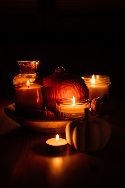 Autumn thanksgiving home decor with pumpkins and burning candles on table dark moody banner