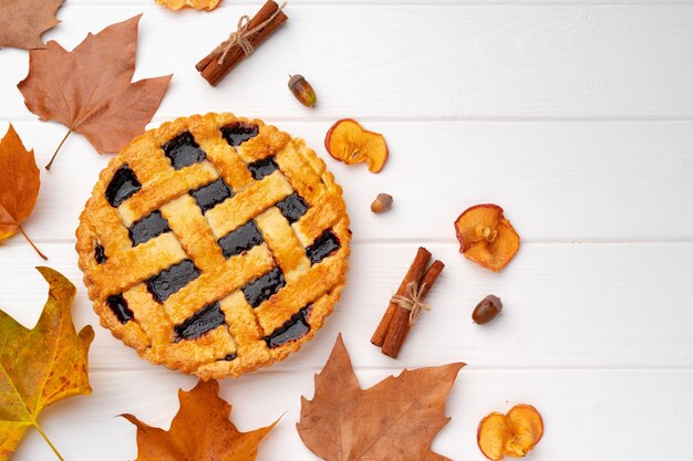 Torta di ringraziamento autunnale sul bordo di legno bianco decorato con foglie secche e bastoncini di cannella